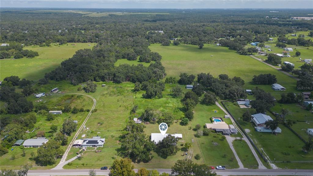 An aerial view shows a single-story house surrounded by large grassy fields and scattered trees — 2630 KEYSVILLE DRIVE, LITHIA, FL