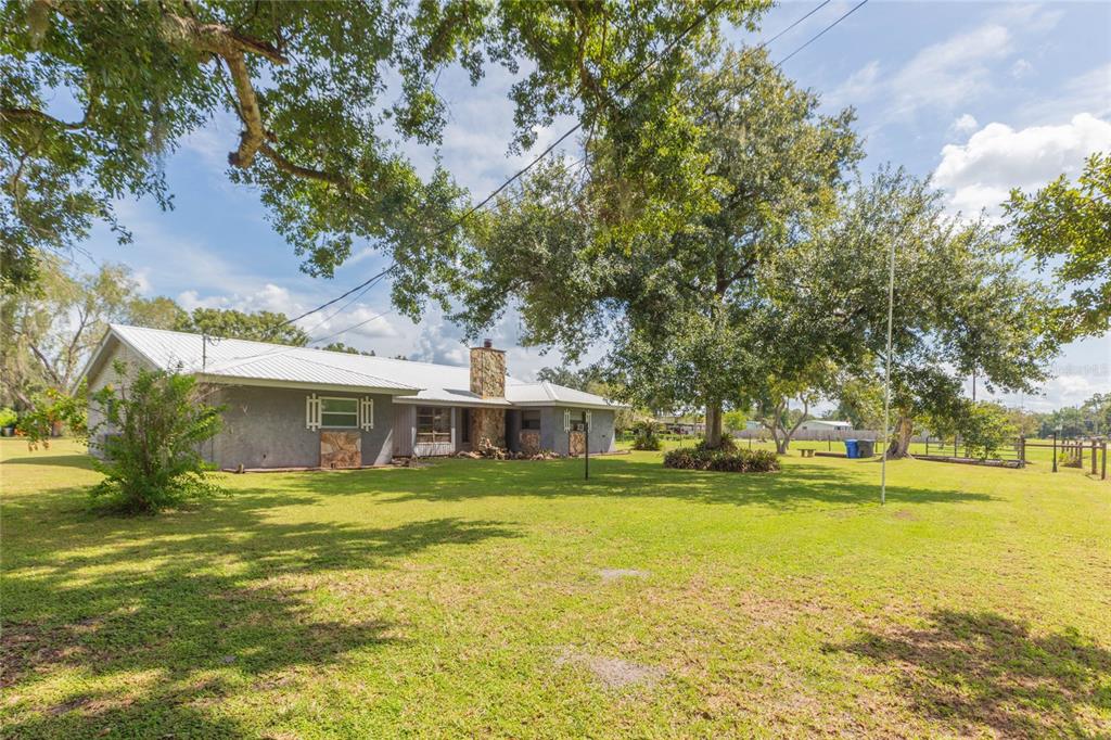 A single-story house with a metal roof and stone chimney sits on a grassy lot — 2630 KEYSVILLE DRIVE, LITHIA, FL