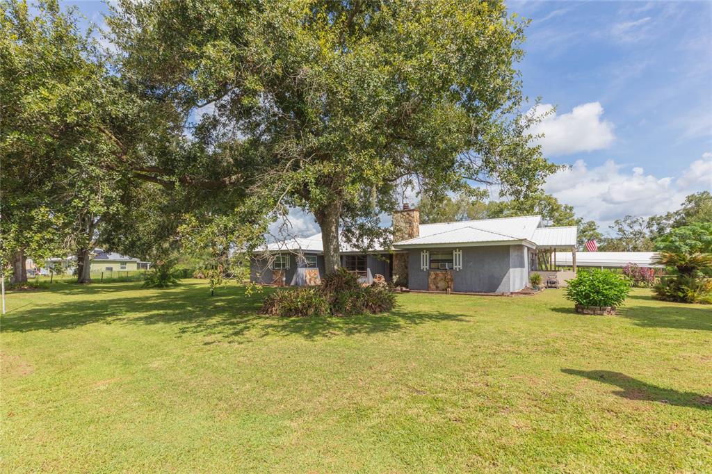 A single-story house with a stone chimney sits on a large, grassy lot with trees — 2630 KEYSVILLE DRIVE, LITHIA, FL