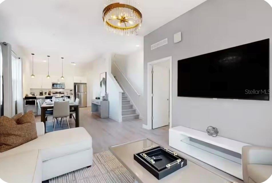 A modern living room and dining area with light wood floors, white walls, and stairs — 613 TRIKOMO DRIVE, DAVENPORT, FL
