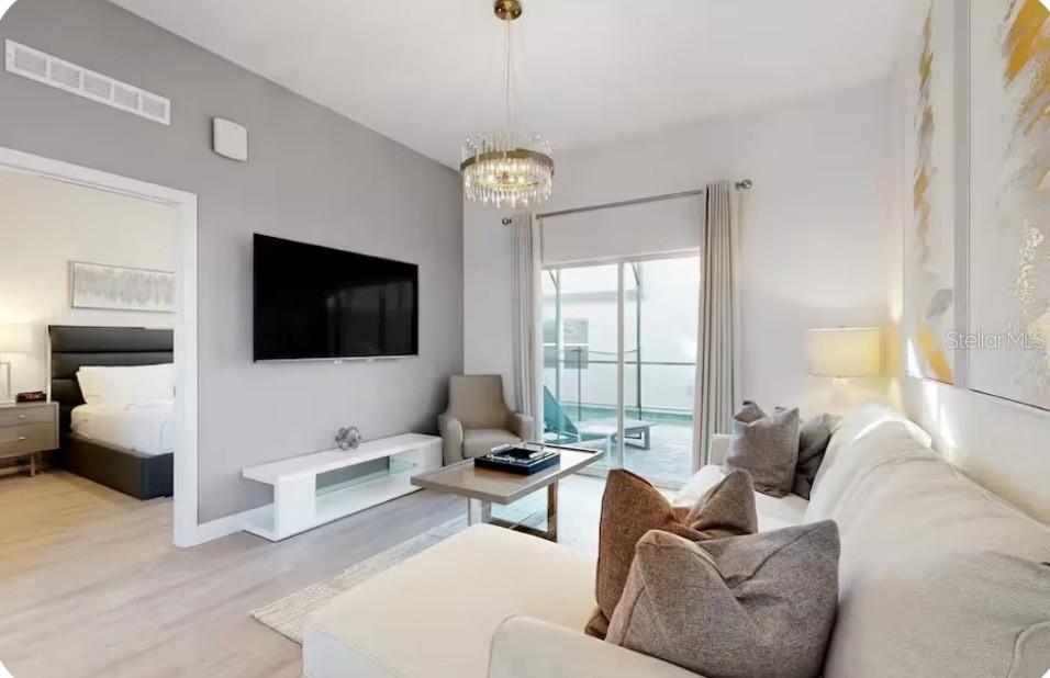 A living room with a sectional sofa, wall-mounted television, and sliding doors to a patio — 613 TRIKOMO DRIVE, DAVENPORT, FL