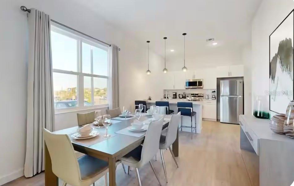 A dining area with a table and chairs leads into a kitchen with stainless appliances — 613 TRIKOMO DRIVE, DAVENPORT, FL