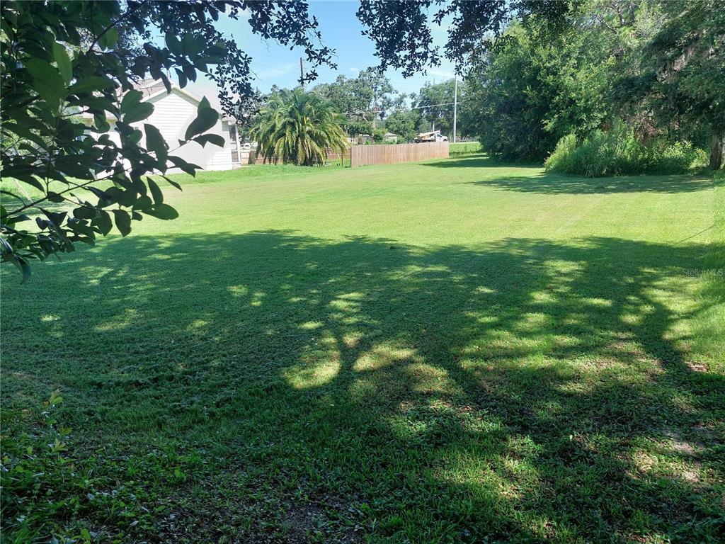 A large, grassy vacant lot with trees and a wooden fence in the background — WALDO, DADE CITY, FL