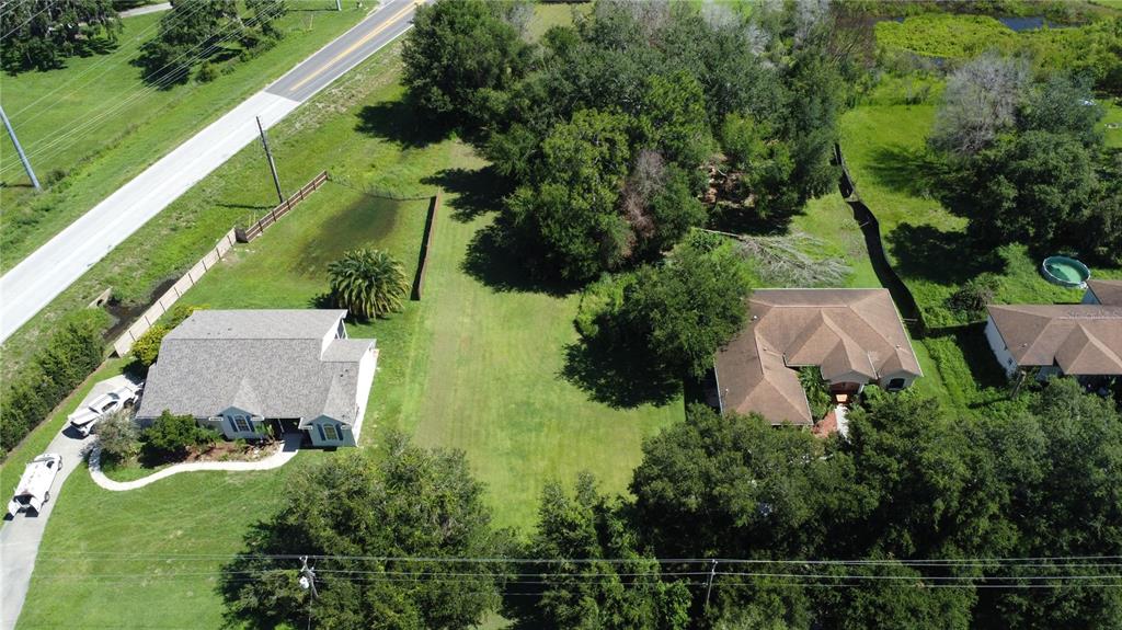 An aerial view shows two houses separated by a large, grassy lot near a road — WALDO, DADE CITY, FL