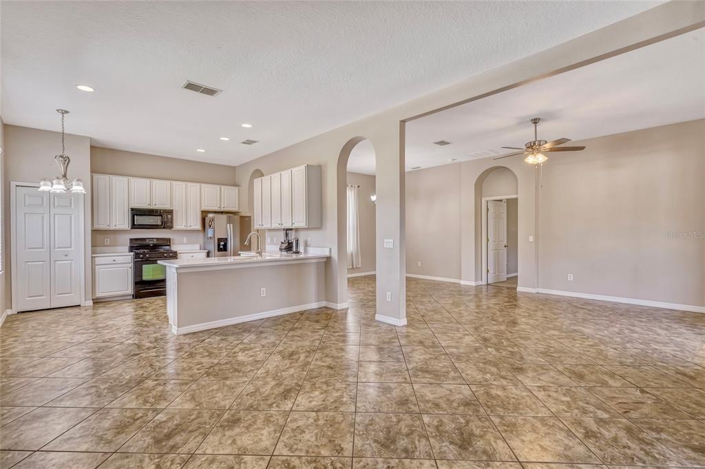 A kitchen features white cabinets, a quartz island with a sink, and a breakfast nook — 115 CRESCENT MOON DRIVE, GROVELAND, FL