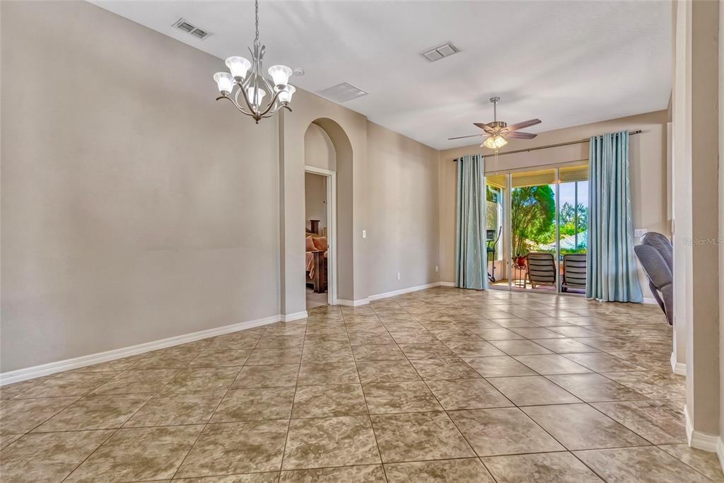 A living room with tile floors opens into a kitchen with white cabinetry and appliances — 115 CRESCENT MOON DRIVE, GROVELAND, FL