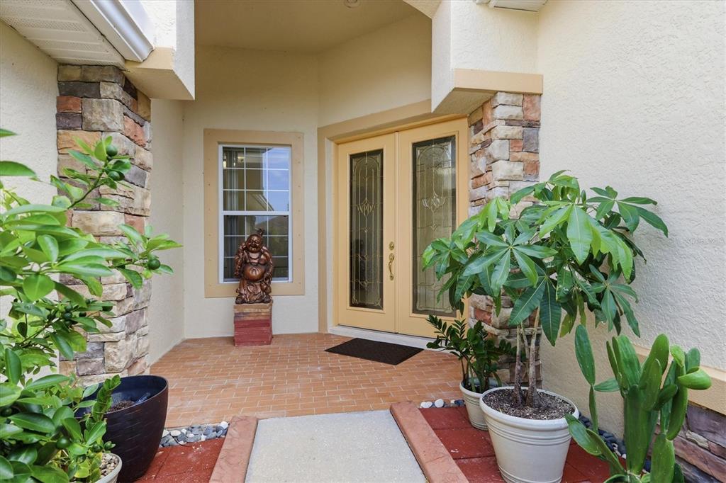 A covered entryway features a double front door, stone pillars, and several potted plants — 4612 62ND AVENUE E, BRADENTON, FL