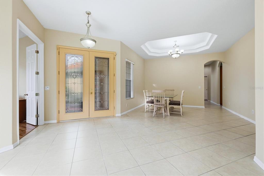 A dining area with tile floors, a tray ceiling, and double glass-paneled front doors — 4612 62ND AVENUE E, BRADENTON, FL