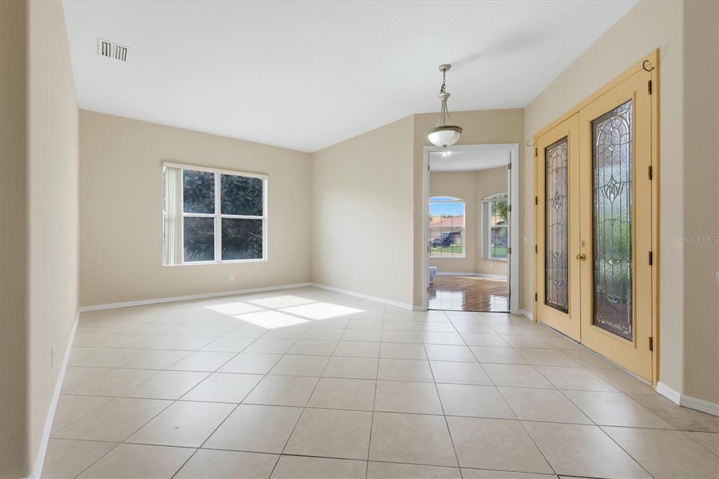 An empty room with beige tile flooring, light-colored walls, and double glass-paneled doors — 4612 62ND AVENUE E, BRADENTON, FL