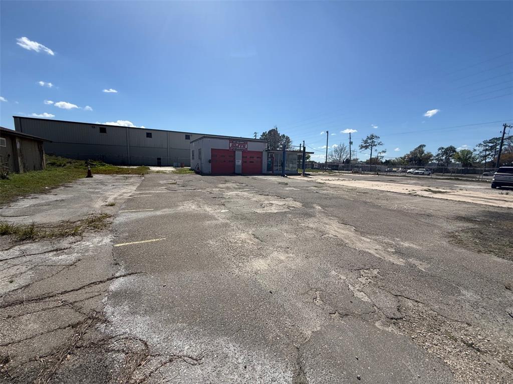 A small commercial building with two red garage doors sits on a large, weathered asphalt lot — 3960 SILVER STAR ROAD, ORLANDO, FL