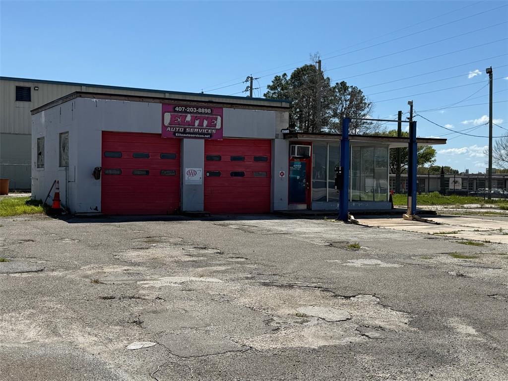 A single-story auto repair shop with two red garage doors and a glass-enclosed office area — 3960 SILVER STAR ROAD, ORLANDO, FL