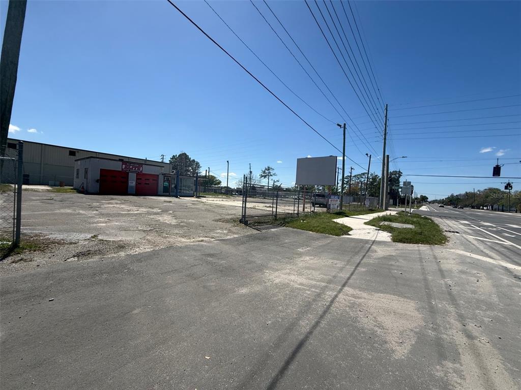 A fenced, paved commercial lot features a small building with red garage doors — 3960 SILVER STAR ROAD, ORLANDO, FL