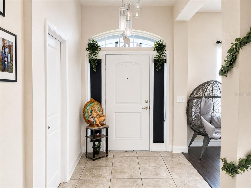 A bright entryway features a white front door, tile flooring, and a hanging egg chair — 4590 BROOKSHIRE PLACE, LAKE WALES, FL
