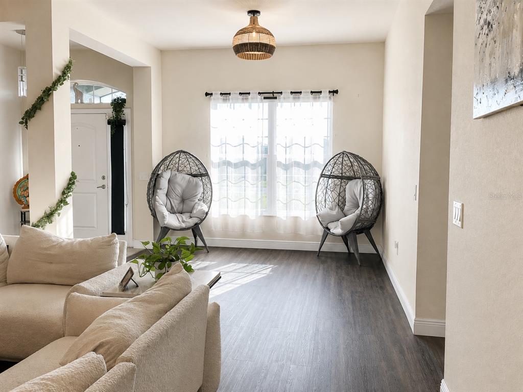A living room features two hanging egg chairs, a light-colored sofa, and dark wood flooring — 4590 BROOKSHIRE PLACE, LAKE WALES, FL