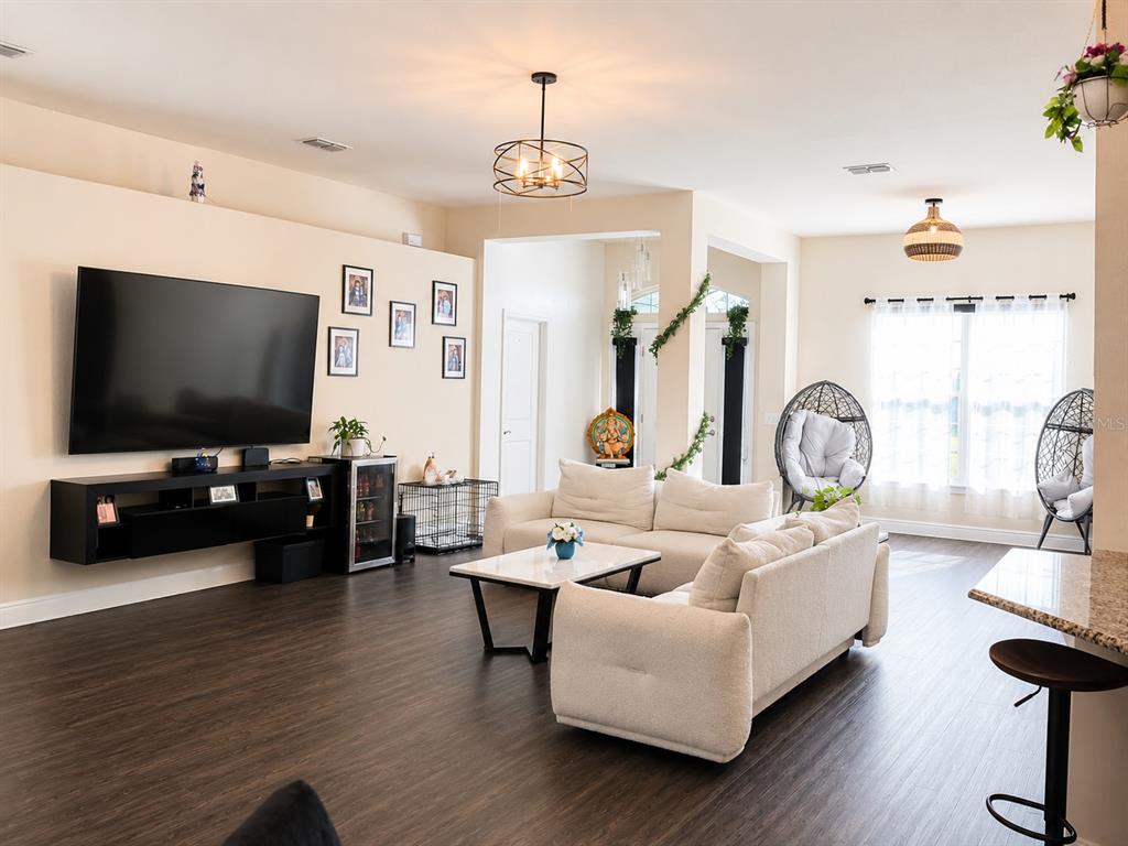 A living room features dark wood flooring, a large wall-mounted television, and a white sectional sofa — 4590 BROOKSHIRE PLACE, LAKE WALES, FL