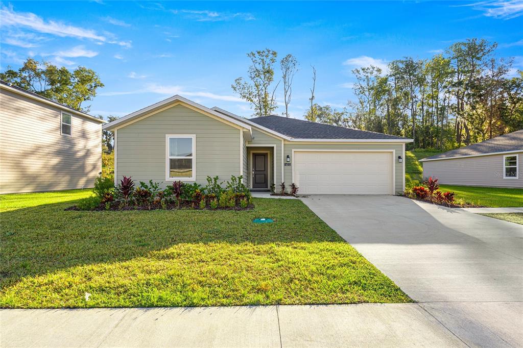 A single-story house with light green siding, a two-car garage, and a front lawn — 16927 NW 144TH STREET, ALACHUA, FL