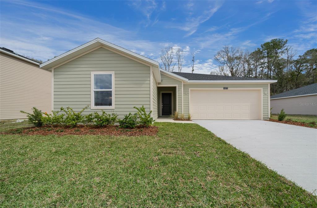 A single-story house with light green siding, a two-car garage, and a front lawn — 16927 NW 144TH STREET, ALACHUA, FL
