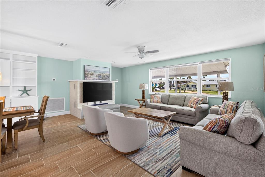 A living room with a gray sofa and a television faces a white front door — 341 PLAZA BOULEVARD, DAYTONA BEACH, FL