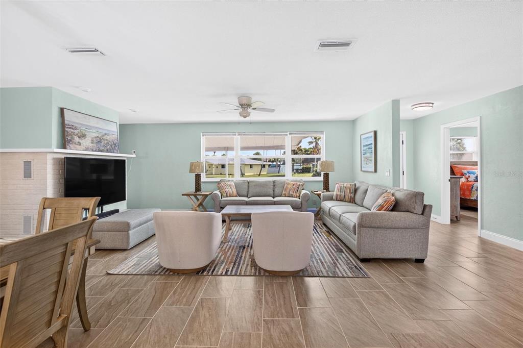 A living room with light blue walls, a white brick fireplace, and gray furniture — 341 PLAZA BOULEVARD, DAYTONA BEACH, FL
