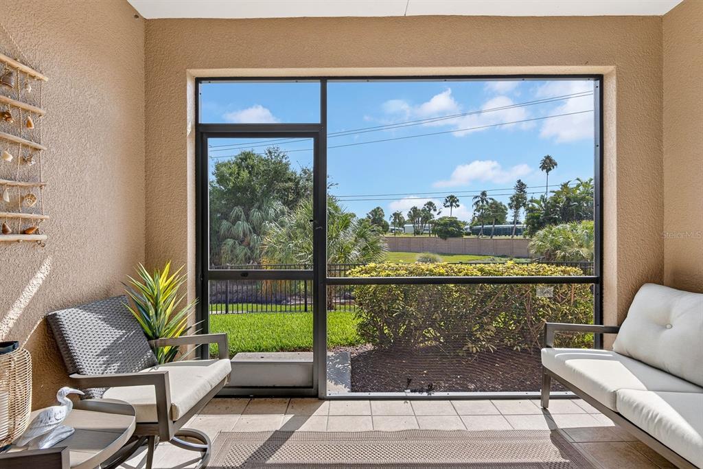 A paved walkway leads between two stucco walls lined with green shrubs toward two doors — 7228 HAMILTON ROAD UNIT 7228, BRADENTON, FL