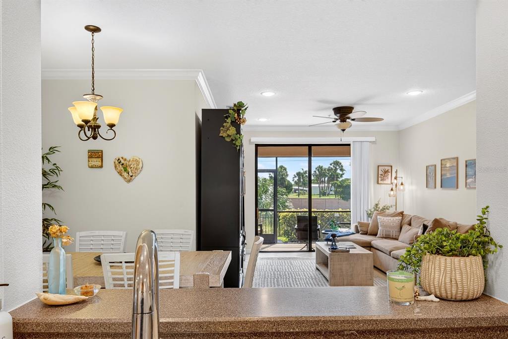 A kitchen with wood cabinets and tile floors opens into a living room with balcony access — 7228 HAMILTON ROAD UNIT 7228, BRADENTON, FL