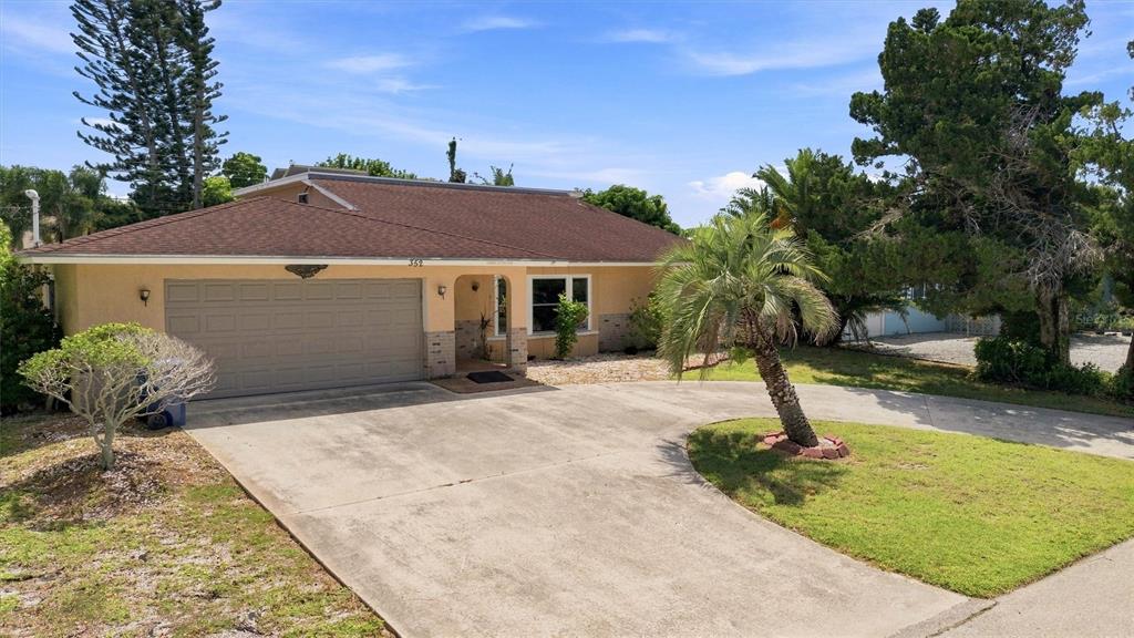 A single-story house with a tan stucco exterior, a brown roof, and a concrete driveway — 352 LAKE ROAD, VENICE, FL