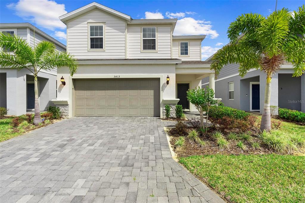 A two-story house with a paved driveway, a two-car garage, and palm trees — 3413 LILAC, DAVENPORT, FL