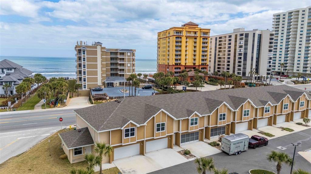 An aerial view shows a multi-unit townhouse complex situated across from beachside buildings and ocean — 108 OCEANS CIRCLE, DAYTONA BEACH, FL