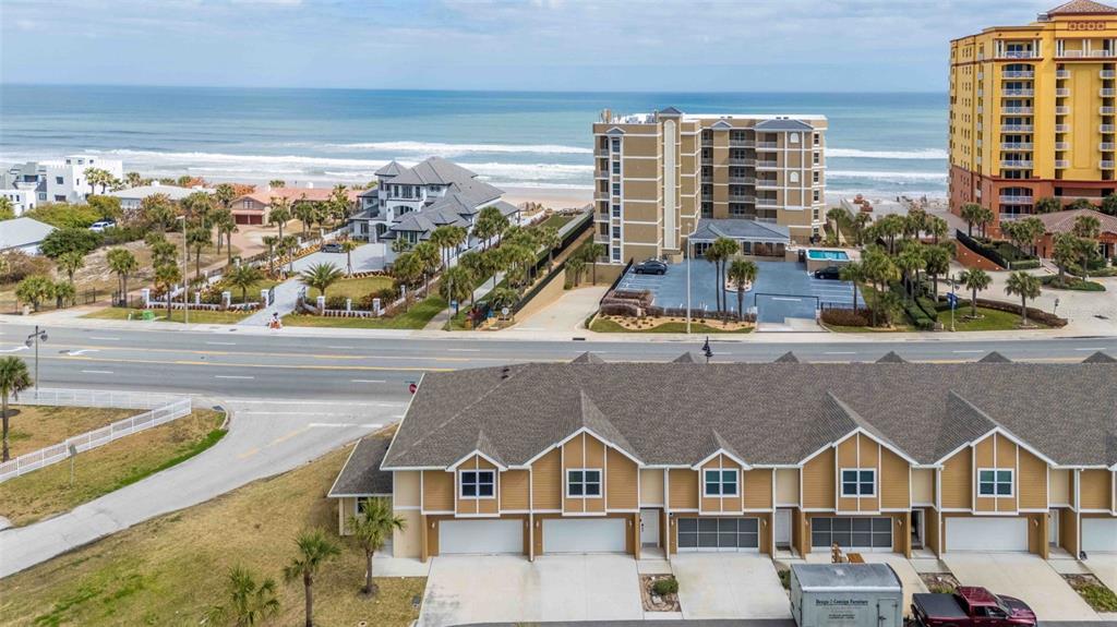 An aerial view shows a row of townhomes in the foreground facing a coastal road — 108 OCEANS CIRCLE, DAYTONA BEACH, FL