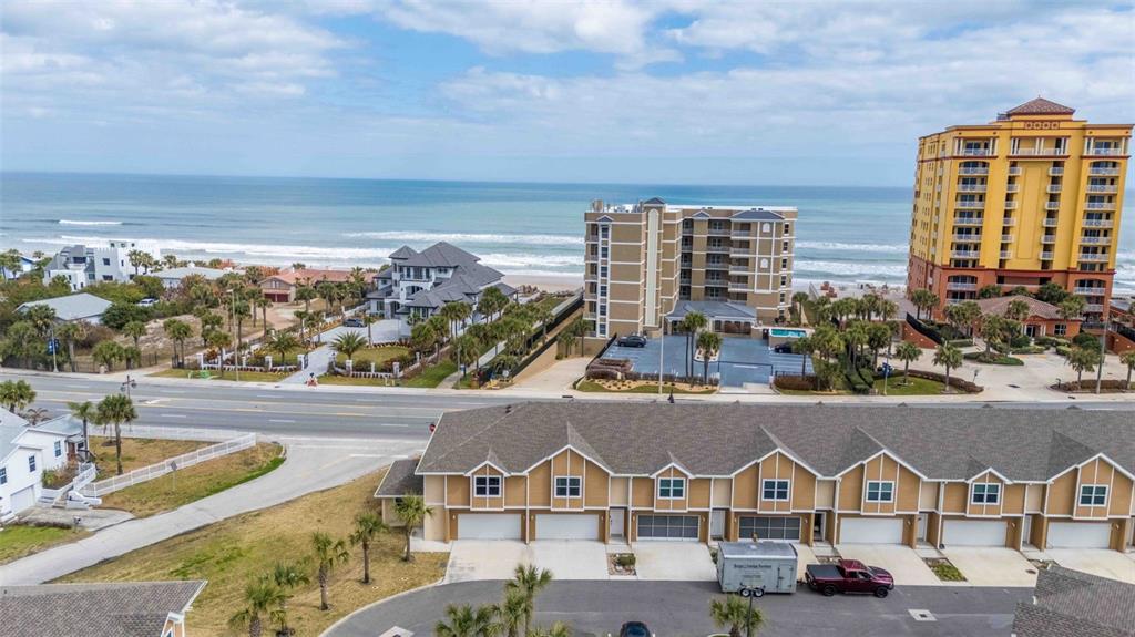 An exterior view of a multi-unit townhouse complex with attached garages at sunset — 108 OCEANS CIRCLE, DAYTONA BEACH, FL