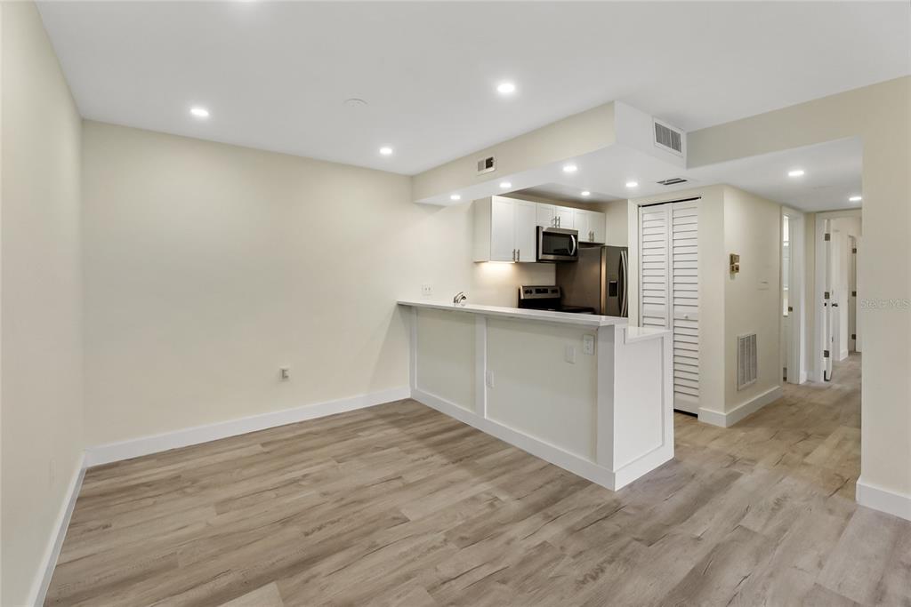 A kitchen with white cabinets and a breakfast bar opens to a living area — 3229 BENEVA ROAD UNIT 203, SARASOTA, FL