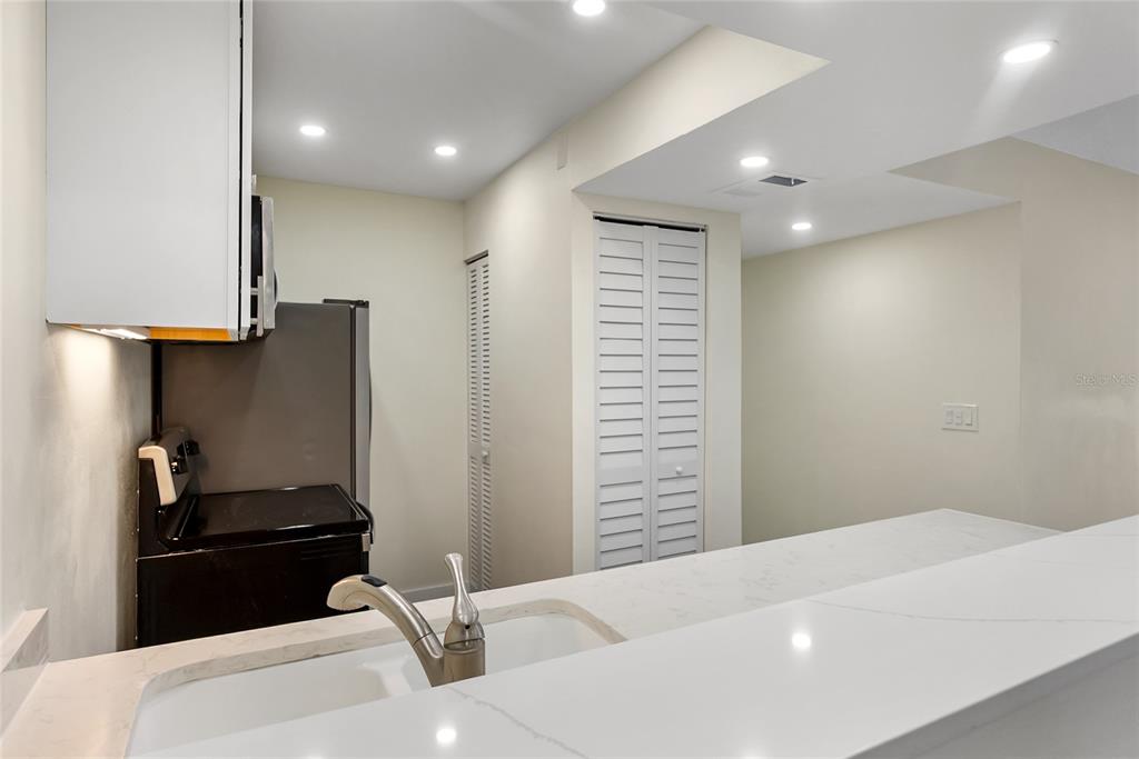 A kitchen features white countertops, a sink, a black stove, and white louvered closet doors — 3229 BENEVA ROAD UNIT 203, SARASOTA, FL