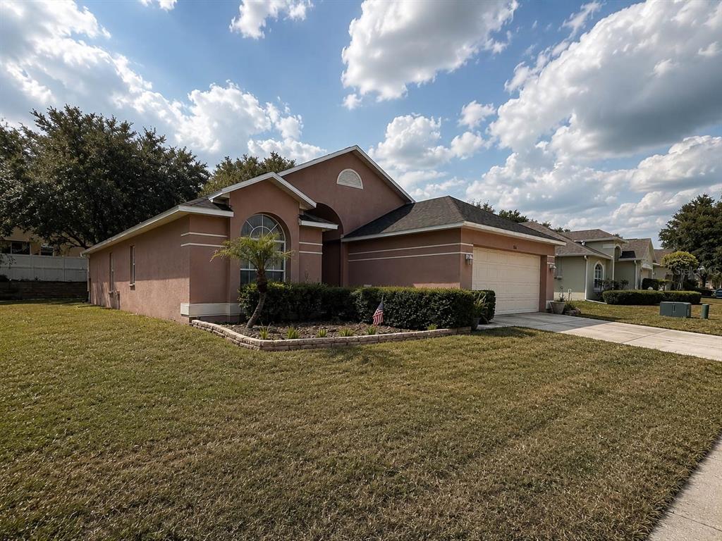 A single-story stucco house with a two-car garage and a landscaped front yard — 5102 AYRSHIRE DRIVE, SPRING HILL, FL
