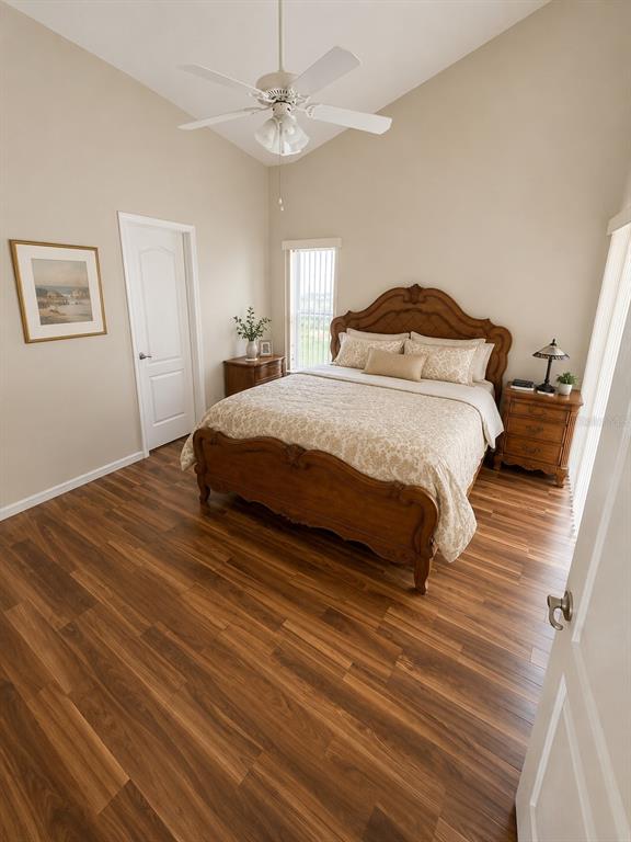 A bedroom features a wooden bed frame, wood-look flooring, a ceiling fan, and neutral walls — 5102 AYRSHIRE DRIVE, SPRING HILL, FL