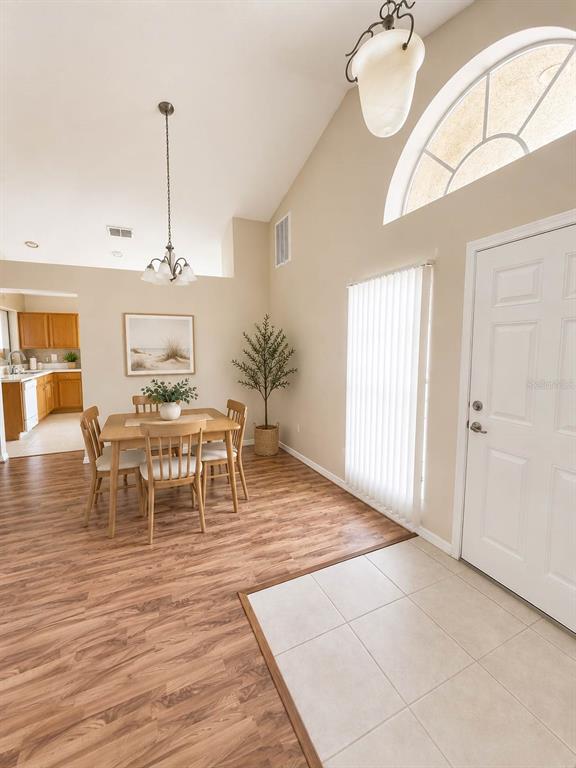 A dining area with wood-look flooring, a table for four, and an adjacent tiled entryway — 5102 AYRSHIRE DRIVE, SPRING HILL, FL