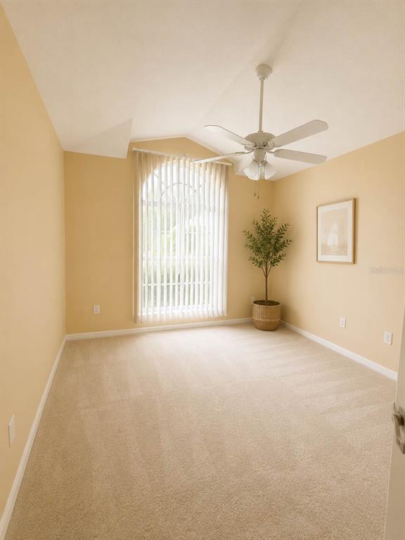 A carpeted room with beige walls, a vaulted ceiling, a ceiling fan, and an arched window — 5102 AYRSHIRE DRIVE, SPRING HILL, FL