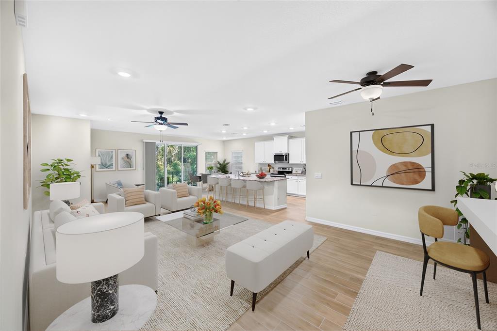 An open-concept living room and kitchen featuring light wood floors, white cabinetry, and neutral furniture — 13639 NW 13TH PLACE, NEWBERRY, FL
