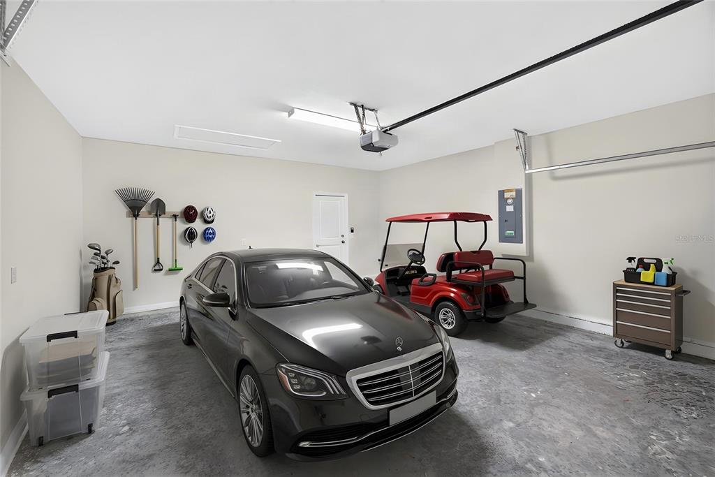 A garage contains a black sedan, a red golf cart, storage bins, and wall-mounted tools — 13639 NW 13TH PLACE, NEWBERRY, FL