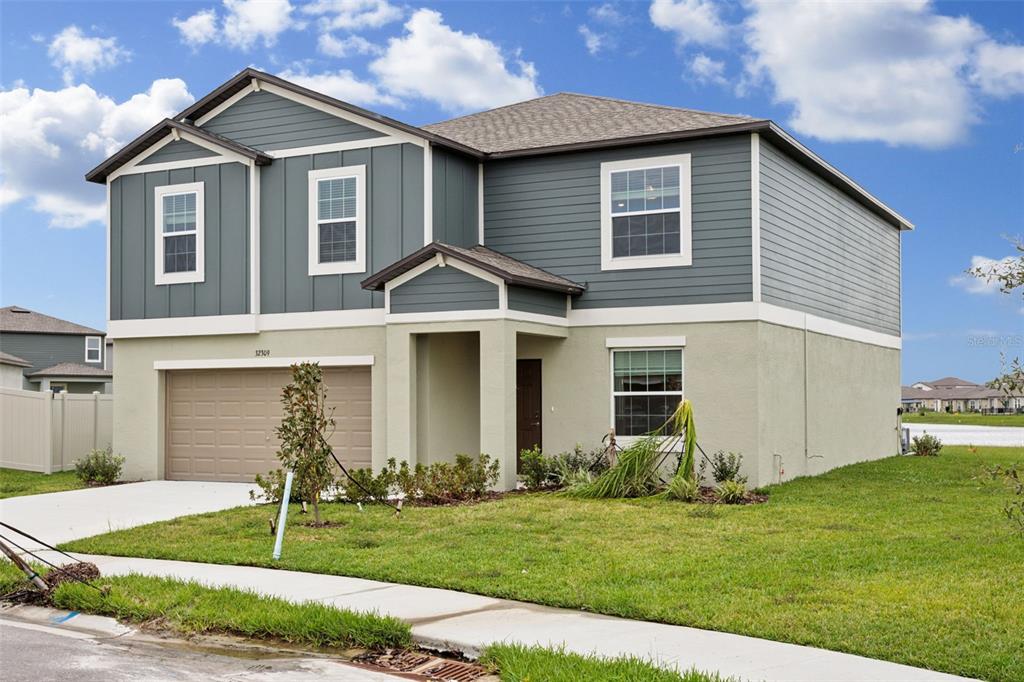 A two-story house with a tan stucco lower level, blue siding upper level, and garage — 32309 WISHING HAVEN DRIVE, SAN ANTONIO, FL