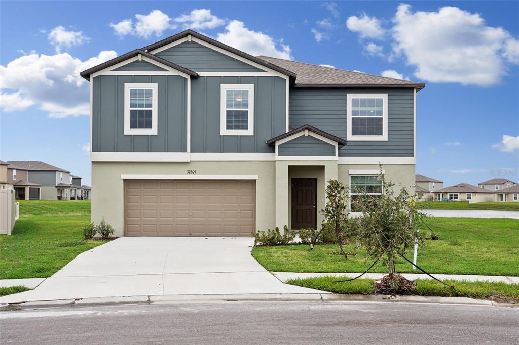 A two-story house with a blue-gray upper level, beige lower level, and a two-car garage — 32309 WISHING HAVEN DRIVE, SAN ANTONIO, FL