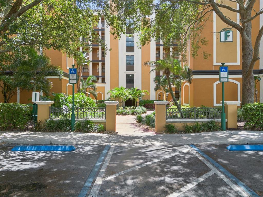 A multi-story apartment building exterior features a central walkway, landscaping, and two handicap parking spaces — 12521 FLORIDAYS RESORT DRIVE UNIT 205F, ORLANDO, FL