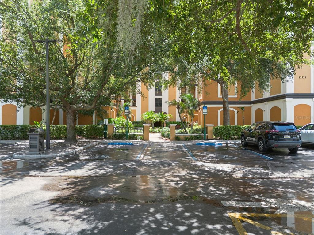 A parking lot with two handicap-accessible spaces sits in front of a multi-story apartment building — 12521 FLORIDAYS RESORT DRIVE UNIT 205F, ORLANDO, FL