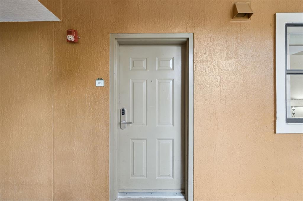 A beige exterior door with a digital lock is set into a textured tan wall — 12521 FLORIDAYS RESORT DRIVE UNIT 205F, ORLANDO, FL