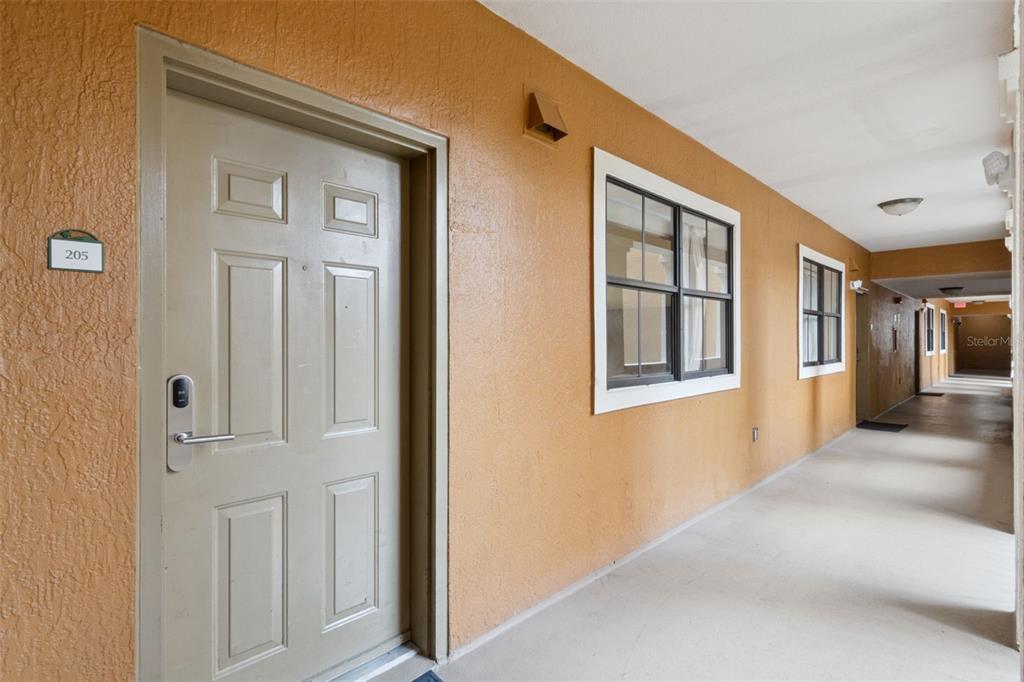 An exterior hallway with a tan door labeled 205, windows, and a concrete walkway — 12521 FLORIDAYS RESORT DRIVE UNIT 205F, ORLANDO, FL
