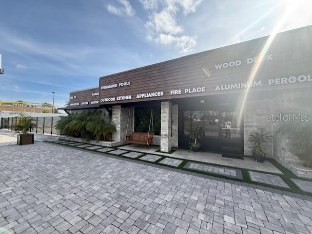 The exterior of a commercial building features stone accents, wood siding, and a paved patio — 3852 L B MCLEOD ROAD, ORLANDO, FL
