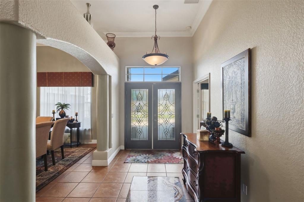 A tiled entryway features double glass-paneled front doors, a hanging pendant light, and arched columns — 1051 DUNBAR AVENUE, SANFORD, FL