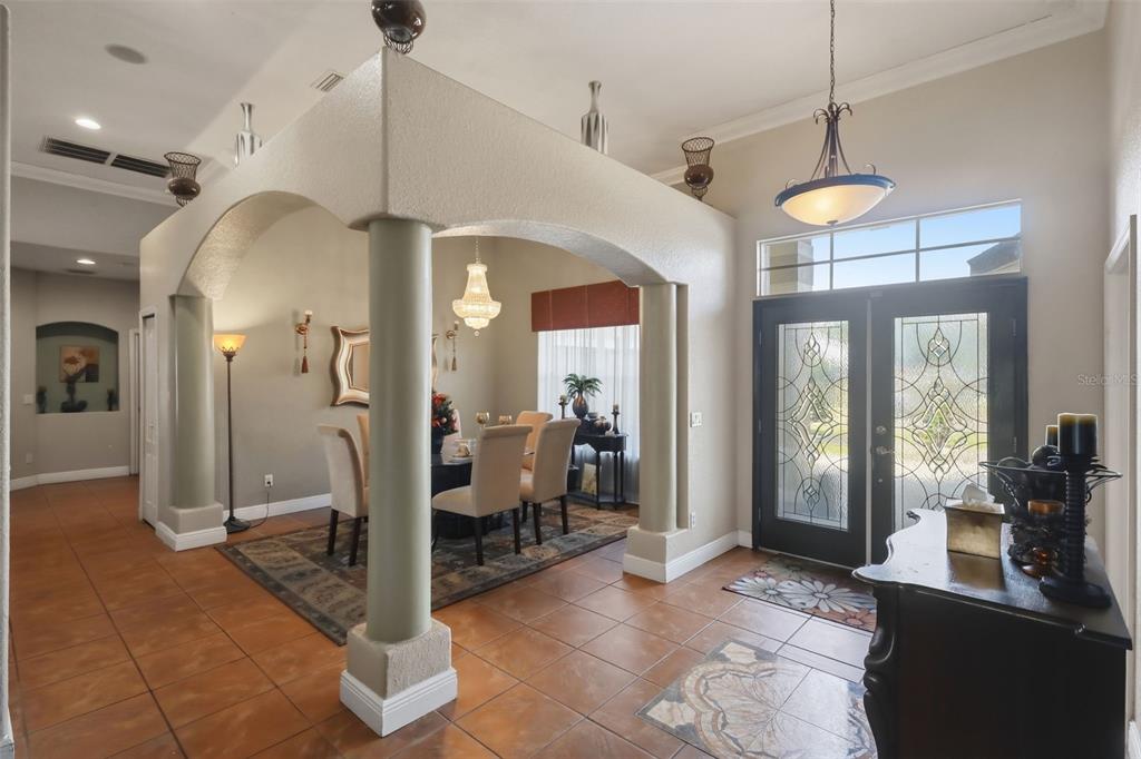 An entryway with tile floors leads to a dining area framed by decorative arched columns — 1051 DUNBAR AVENUE, SANFORD, FL