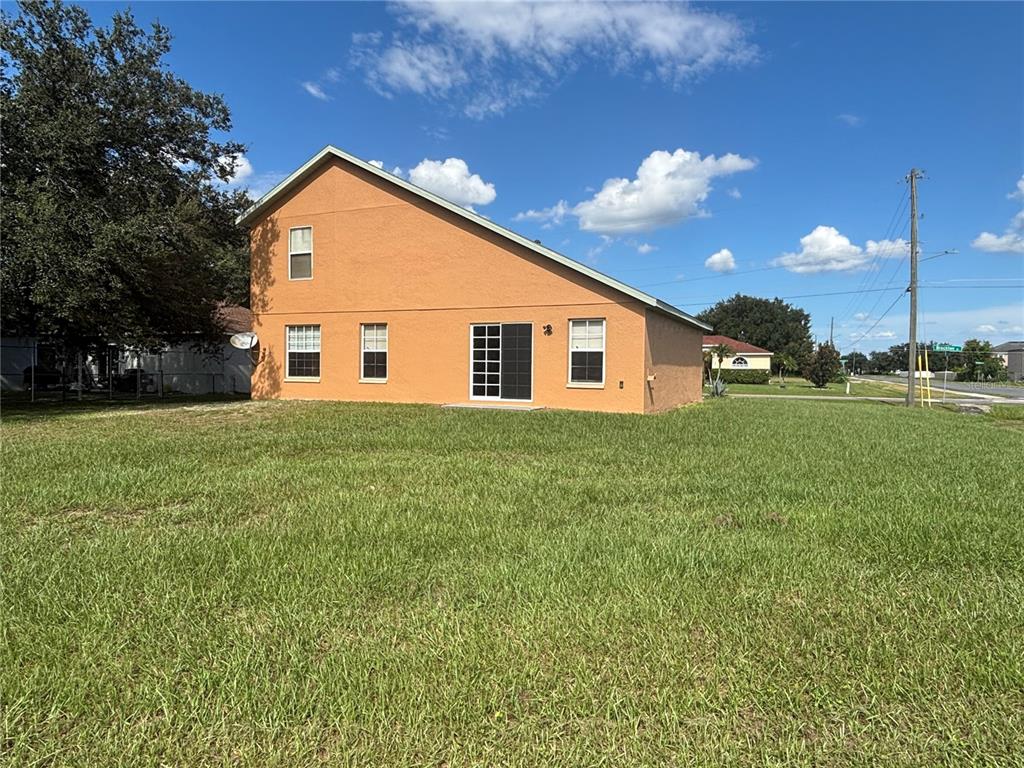The exterior of a two-story orange stucco house with a sliding glass door and windows — 664 BROCKTON DRIVE, KISSIMMEE, FL