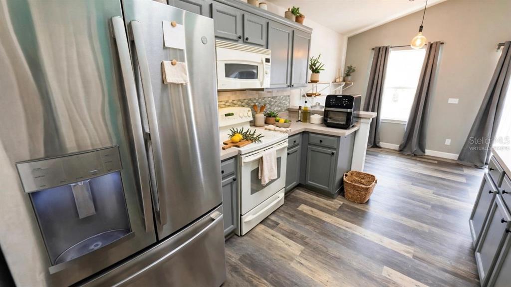 A kitchen features gray cabinets, stainless steel appliances, and wood-look flooring — 664 BROCKTON DRIVE, KISSIMMEE, FL