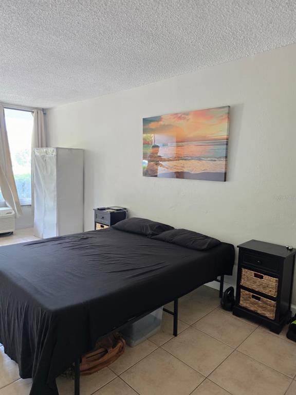 A bedroom features a bed with black bedding, two nightstands, and a sunset wall canvas — 7900 S ORANGE BLOSSOM TRAIL UNIT 1055, ORLANDO, FL